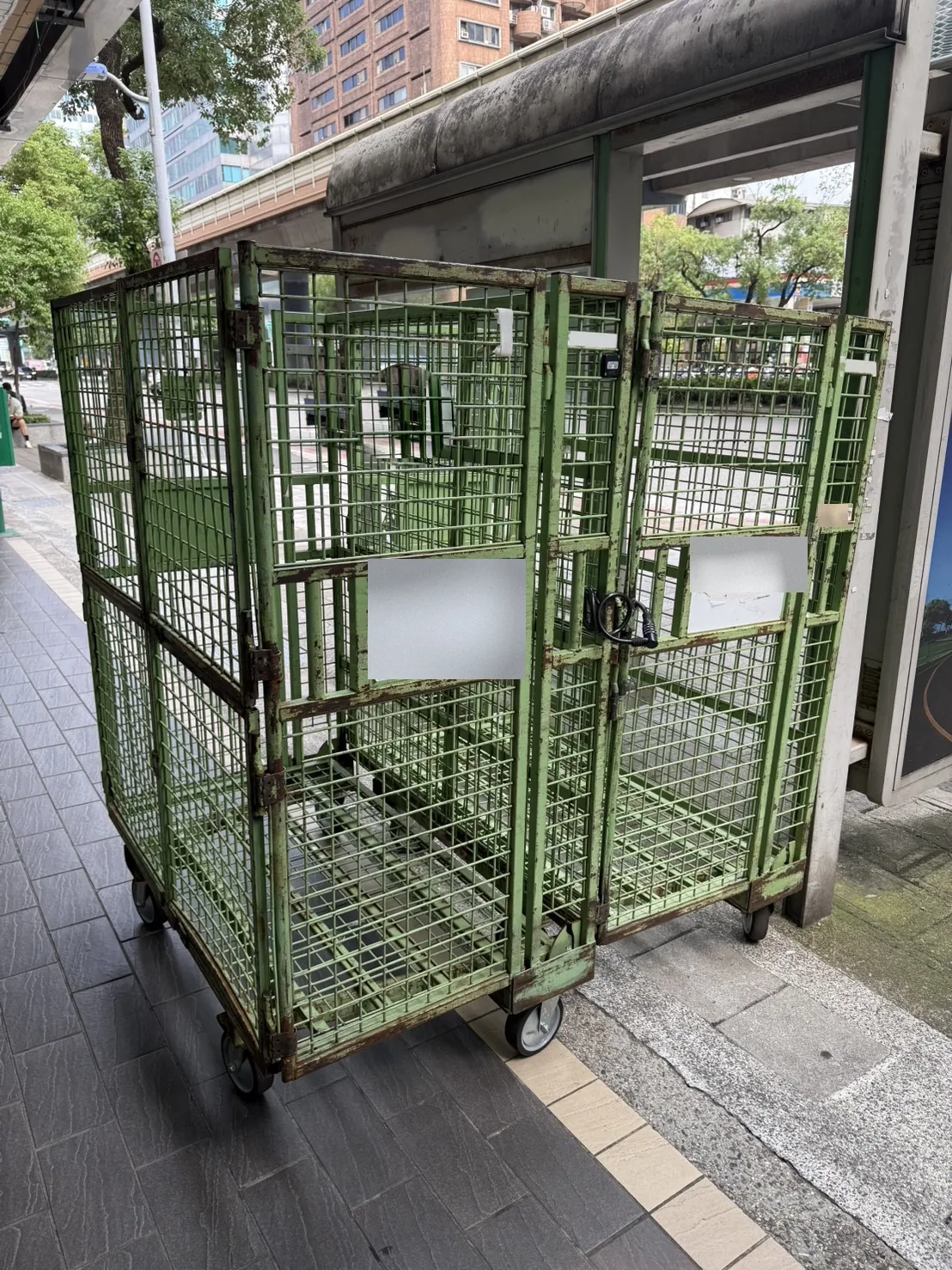 兩台停放在人行道邊的物流籠車，籠車鋼架上裝有藍牙追蹤標籤
